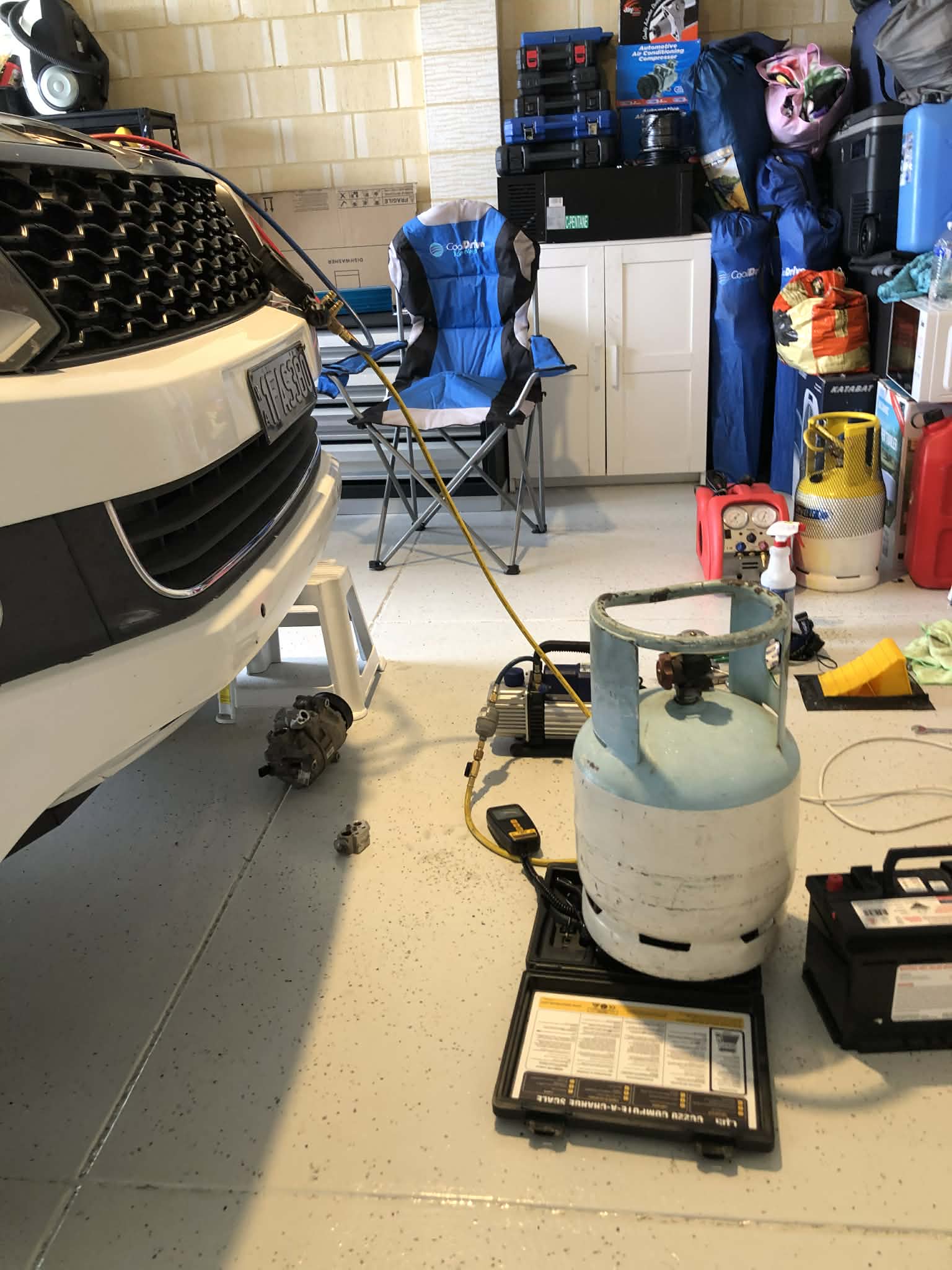White vehicle undergoing air conditioning service with hoses connected