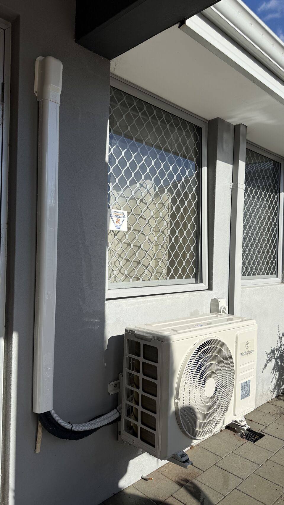 Outdoor unit installed in a narrow side alcove with pipework run to the roof